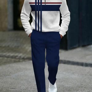 May include: A white long-sleeve shirt with a zipper closure and blue and red stripes. The shirt is paired with matching blue pants.