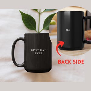 May include: Black ceramic mug with the text "BEST DAD EVER" in white. The back of the mug has a heart symbol and the letter "G". The mug has a large handle and is suitable for hot or cold beverages.