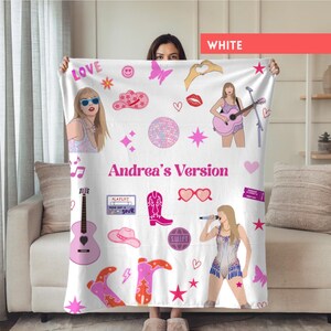 May include: White blanket with pink and purple illustrations, including a woman with sunglasses, a guitar, cowboy boots, and the text "Andrea's Version". The blanket has a variety of other graphics, such as hearts, stars, and a disco ball.