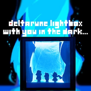 Könnte beinhalten: Eine blau beleuchtete Leuchtbox mit Silhouetten von Charakteren aus Deltarune. Der Text "Deltarune lightbox with you in the dark..." ist in weißer Pixel-Schrift dargestellt. Der Hintergrund ist schwarz mit blauen flammenartigen Formen.