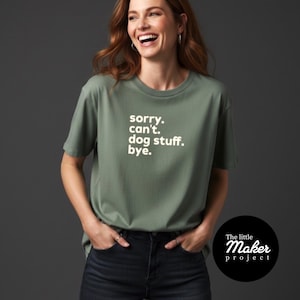 Peut inclure: T-shirt vert olive avec l'inscription blanche : "sorry. can't. dog stuff. bye.". Le t-shirt est de style col rond et est porté par une personne. Le logo The Little Maker Project est en bas à droite.