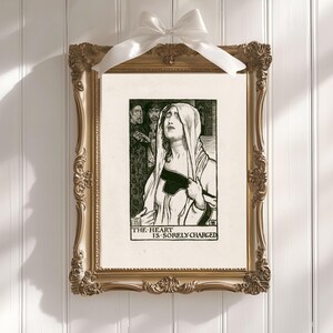 May include: A black and white illustration of a woman in a hooded cloak, with the text "THE HEART IS SORELY CHARGED" below. The illustration is framed in a gold frame.