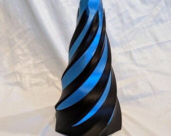 May include: A 3D-printed sculpture with a spiraling design. The sculpture features alternating bands of black and blue, creating a visually striking effect. The object has a pointed top and a geometric base.