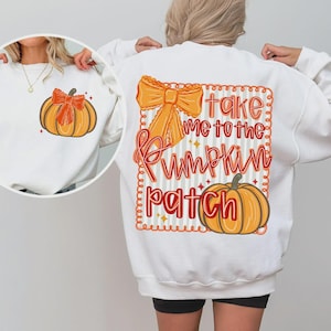 May include: White sweatshirt with a pumpkin graphic on the front and back. The back features a large orange bow, a pumpkin, and the text "take me to the pumpkin patch" in red and orange.