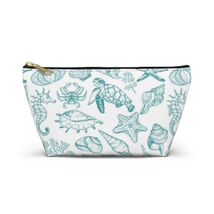 May include: A white zippered pouch with a teal blue pattern of sea life, including seahorses, starfish, seashells, and a turtle.