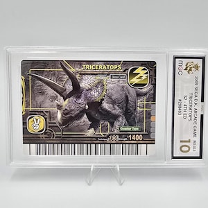 Puede incluir: Una tarjeta coleccionable calificada con un dinosaurio Triceratops del juego arcade Sega D.K. de 2009. La tarjeta est&aacute; dentro de un soporte de pl&aacute;stico transparente y tiene una calificaci&oacute;n de 10. El dise&ntilde;o de la tarjeta incluye la palabra "TRICERATOPS" y el texto "Dino Card".