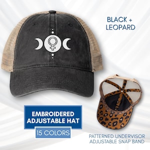 May include: Black trucker hat with a beige mesh back and a patterned leopard under-visor. The front of the hat features an embroidered design of a triple moon symbol and a female symbol. The text "BLACK + LEOPARD" is visible.