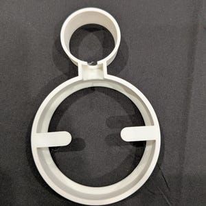 Puede incluir: Un soporte para dispositivo de pl&aacute;stico blanco que presenta un anillo circular grande con dos pesta&ntilde;as orientadas hacia adentro y un anillo m&aacute;s peque&ntilde;o unido a la parte superior. El texto "DEVICE MOUNTS SERIES" aparece en la esquina superior derecha.