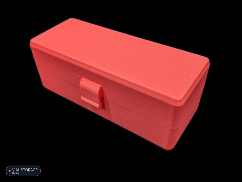 May include: A rectangular coral-colored storage box with a hinged lid and a central latch mechanism. The box features a textured surface consistent with 3D-printed construction. A small label in the corner displays the text VIAL STORAGE SERIES.