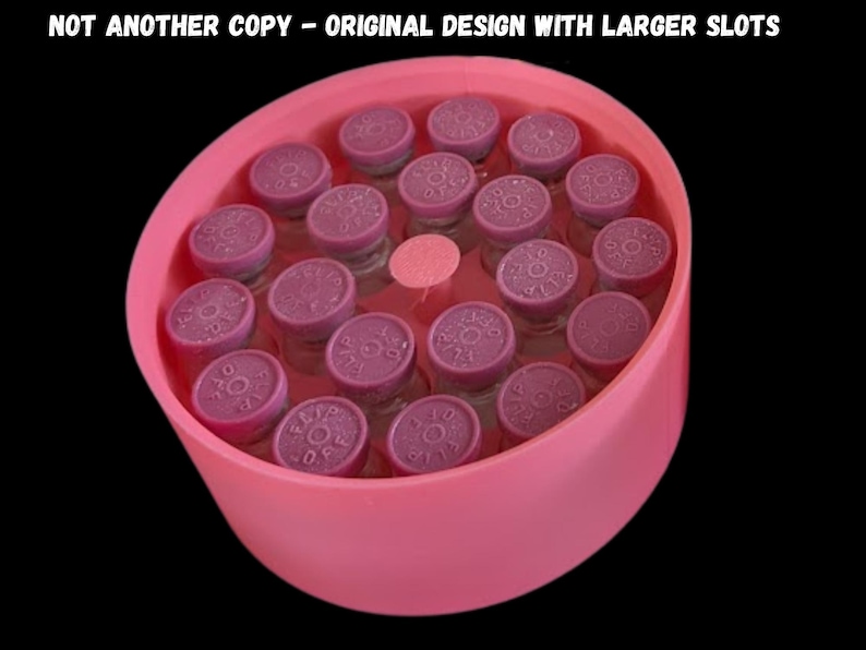May include: A pink circular storage container holding nineteen small glass vials with purple flip-off caps. The text NOT ANOTHER COPY - ORIGINAL DESIGN WITH LARGER SLOTS is printed at the top. The container has individual slots for each vial.