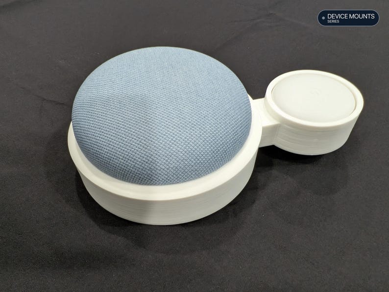 Puede incluir: Un altavoz inteligente cubierto de tela azul claro montado en un soporte circular de pl&aacute;stico blanco con una base circular blanca m&aacute;s peque&ntilde;a adjunta. El texto "DEVICE MOUNTS SERIES" es visible en la esquina superior derecha.