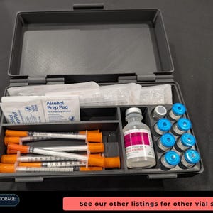 以下が含まれることがあります： オレンジ色のキャップが付いた注射器4本、ピンクのラベルが貼られたガラス瓶1本、青いキャップの小さな瓶8本、個包装された白いアルコール綿など、医療用品が入ったダークグレーのプラスチック製収納ケース。