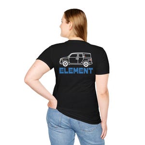 May include: Black t-shirt featuring a white outline of a vehicle with the word "ELEMENT" in blue block letters. The shirt is a crew neck and is being worn by a person.
