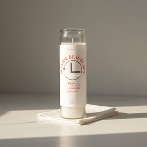 May include: A tall, cylindrical glass candle filled with white wax, featuring a white label with red and black text. The label displays the text REVERSE BEAUTY HEX, a circular logo with an L, and the words GO IN WAY, Come To Me, STRENGTH, High Confidence.