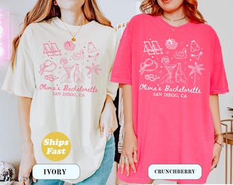 May include: Ivory and Crunchberry t-shirts with a pink graphic design. The design includes beach chairs, a sun hat, cocktails, and the text "Olivia's Bachelorette, San Diego, CA".