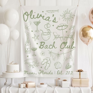 May include: A white banner with green illustrations and text for a hen party. The banner features drawings of a sun, cocktails, beach chairs, and swimwear. The text reads "Olivia's Bach Club Miami, Florida | Est. 2021". White and gold balloons and gifts are also present.