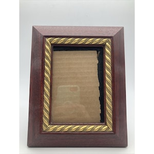 May include: A rectangular wooden picture frame with a dark reddish-brown finish. The frame has a gold-colored rope-like trim around the inner edge. The frame is empty, with a cardboard backing visible.