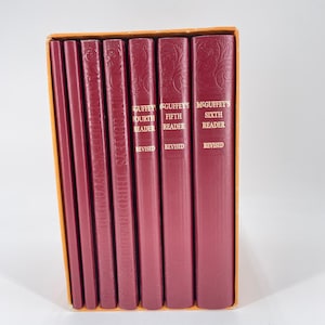 May include: A set of McGuffey's Readers in a box. The books are a deep red color with gold lettering and decorative embossed patterns. The set includes the Fourth, Fifth, and Sixth Readers, all revised editions.