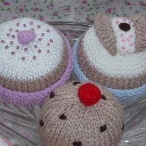 Knitted cakes, currant buns, fairy cakes, cupcakes, butterfly cakes, on a cake stand plate