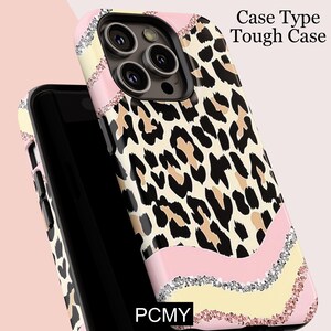 Peut inclure: Une coque de t&eacute;l&eacute;phone r&eacute;sistante avec un motif l&eacute;opard. L'&eacute;tui pr&eacute;sente un accent rose, jaune et argent&eacute; scintillant. Le texte "Case Type Tough Case" est visible. Les lettres "PCMY" sont &eacute;galement visibles.