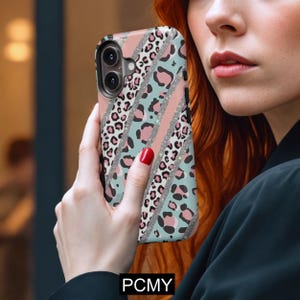 Peut inclure: Coque de t&eacute;l&eacute;phone avec un motif l&eacute;opard rose, turquoise et imprim&eacute;. L'&eacute;tui pr&eacute;sente des rayures diagonales avec des accents de paillettes argent&eacute;es. Le bas de l'&eacute;tui porte le texte "PCMY".