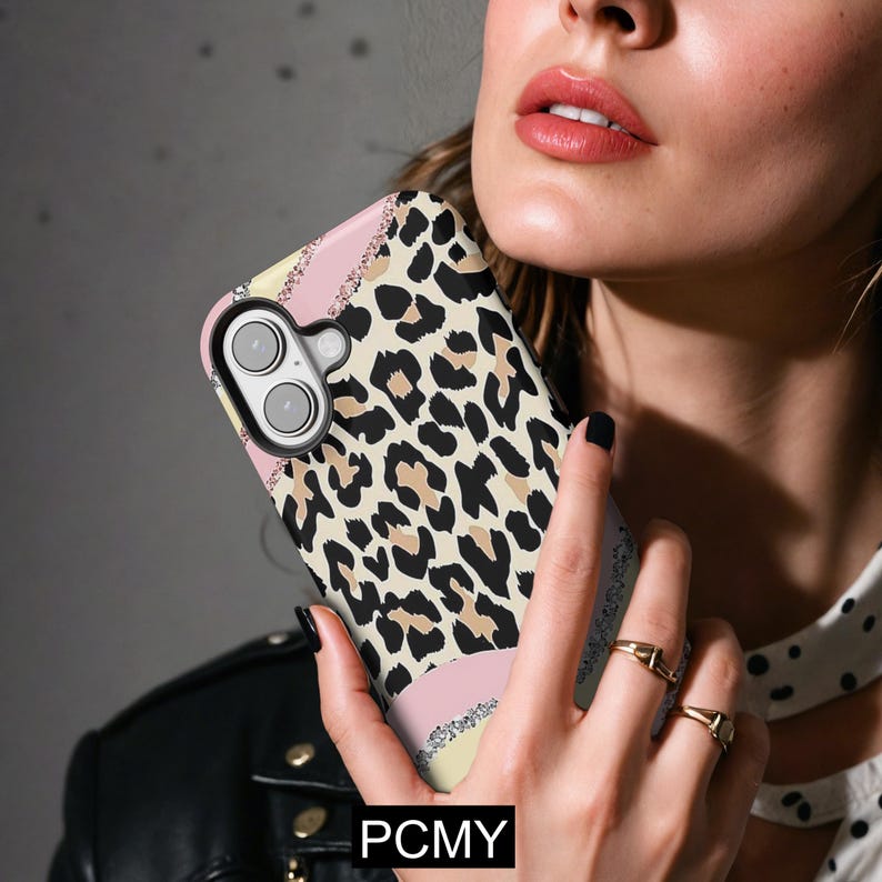 Peut inclure: Une coque de t&eacute;l&eacute;phone avec un motif l&eacute;opard. L'&eacute;tui pr&eacute;sente une bande rose, jaune et argent&eacute;e &agrave; paillettes. Le texte "PCMY" est visible en bas de l'&eacute;tui.
