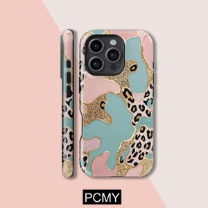 Peut inclure: Coque de t&eacute;l&eacute;phone aux motifs color&eacute;s. Elle pr&eacute;sente des touches de rose, de turquoise et de paillettes dor&eacute;es, avec des d&eacute;tails l&eacute;opard noirs. Le texte "PCMY" est en bas.