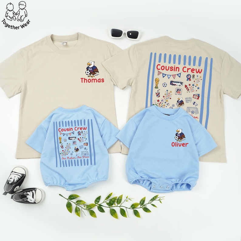 May include: A collection of children's apparel, including two beige t-shirts and two light blue rompers. The t-shirts feature an eagle graphic and the name "Thomas" and "Oliver". The rompers have "Cousin Crew" text and patriotic illustrations.