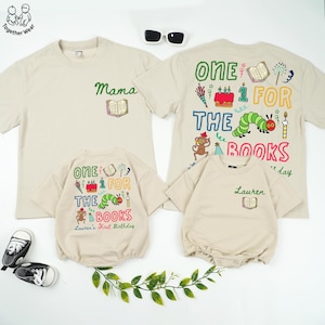 May include: Beige family matching t-shirts and rompers with colorful "One for the Books" graphic designs. The shirts and rompers have a book and birthday theme, with the word "Mama" on one shirt and "Lauren's First Birthday" on the romper.