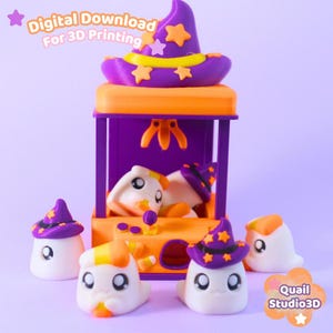 May include: A 3D printed claw machine toy in orange and purple, topped with a purple witch hat featuring orange stars. The machine contains small white ghost figures wearing matching hats, with text reading Digital Download For 3D Printing and Quail Studio3D.