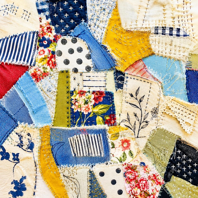 Op de afbeelding: Een textielcollage bestaande uit diverse stukjes stof in blauw, geel, rood en wit. De stukken bevatten bloemenprints, stippen, strepen en denim, allemaal samengevoegd met zichtbaar handgestikt borduurwerk en rijgsteken.