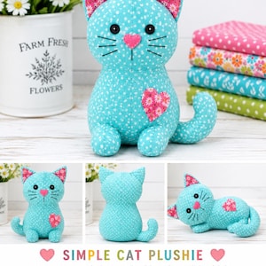 Könnte beinhalten: Ein türkisfarbenes Katzen-Stofftier aus Stoff mit weißem Punktemuster, mit rosafarbenen floralen Innenohren, einer herzförmigen rosa Nase, schwarzen Knopfaugen, gestickten Schnurrhaaren und einem floralen rosa Herzaufnäher auf der Brust, in verschiedenen Posen.