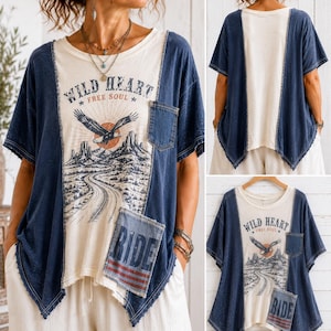 May include: A short-sleeve top featuring a cream-colored center panel with a graphic of an eagle, mountains, and the text "WILD HEART FREE SOUL". The top has dark blue side panels, a chest pocket, and a lower patch pocket with the text "RIDE".