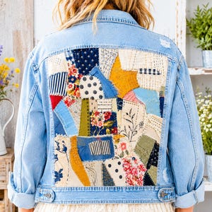 May include: A light blue denim jacket featuring a large back panel composed of various fabric patches in shades of blue, yellow, white, and green. The patchwork includes floral, polka dot, striped, and solid patterns with visible stitching.