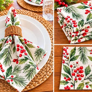May include: A set of square cloth napkins featuring a white background with a printed pattern of green pine needles, dark green leaves, and clusters of bright red berries. The napkins are shown folded, stacked, and displayed on a white plate.