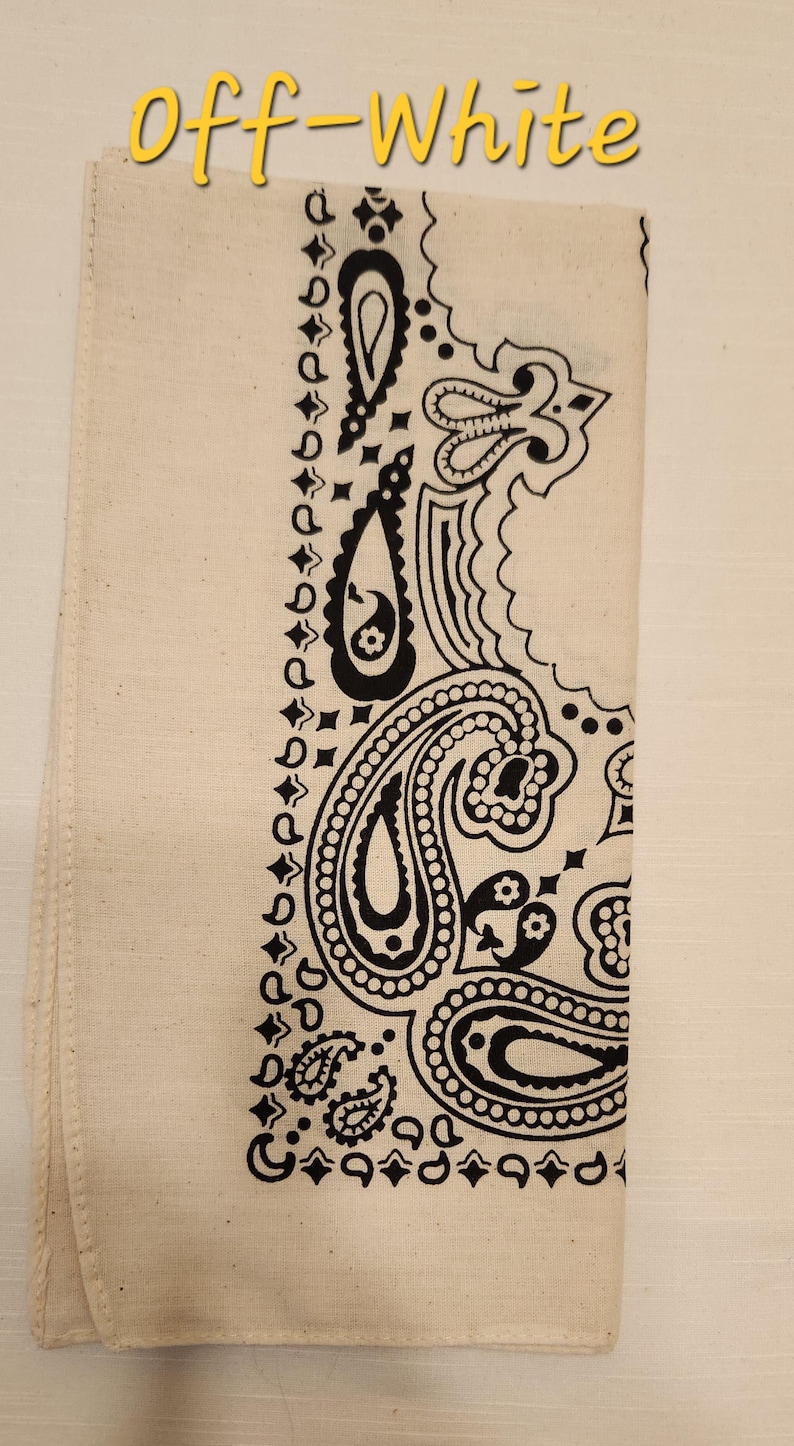 May include: An off-white bandana featuring a black paisley print pattern. The fabric is folded into a rectangular shape. The text "Off-White" is printed in yellow at the top of the image, positioned above the patterned textile accessory.