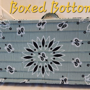May include: A rectangular fabric bag base with a sage green and black paisley bandana print. The quilted construction features horizontal stitching lines and a structured boxed bottom design. The text Boxed Bottom is visible in yellow.