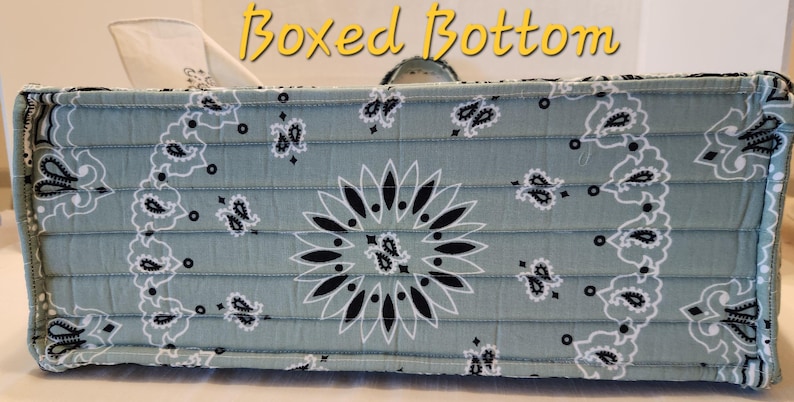 May include: A rectangular fabric bag base with a sage green and black paisley bandana print. The quilted construction features horizontal stitching lines and a structured boxed bottom design. The text Boxed Bottom is visible in yellow.