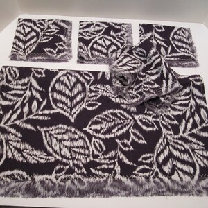 May include: Set of five purple and white patterned fabric placemats with fringed edges. The placemats feature a leaf design.