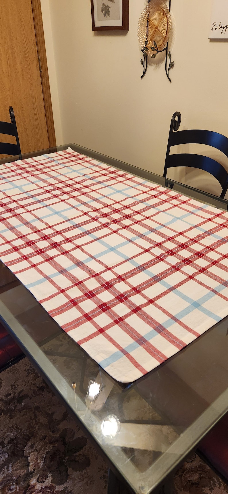 K&ouml;nnte beinhalten: Eine rot-blaue karierter Tischdecke auf einer Glastischplatte. Die Tischdecke ist wei&szlig; mit roten und blauen Streifen.