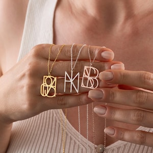 Könnte beinhalten: Drei Halsketten mit Initialen-Anhängern in Gold und Silber. Die goldene Halskette zeigt die Buchstaben "OA", die silberne Halskette hat "NM" und die dritte silberne Halskette zeigt "MB". Jeder Anhänger hängt an einer zarten Kette.