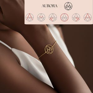 Può includere: Un braccialetto dorato con un pendente circolare con un design geometrico astratto. Il braccialetto, su una catena sottile, è indossato al polso. La parola "AURORA" è visibile in alto a sinistra. Gioielleria.