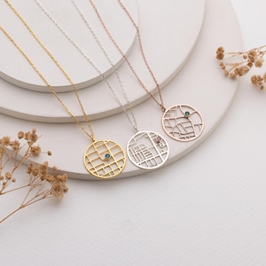 May include: Four delicate necklaces with pendant designs. The pendants are circular, featuring a map-like grid pattern with a gemstone accent. The necklaces are gold, silver, and rose gold in colour, each with a matching chain.