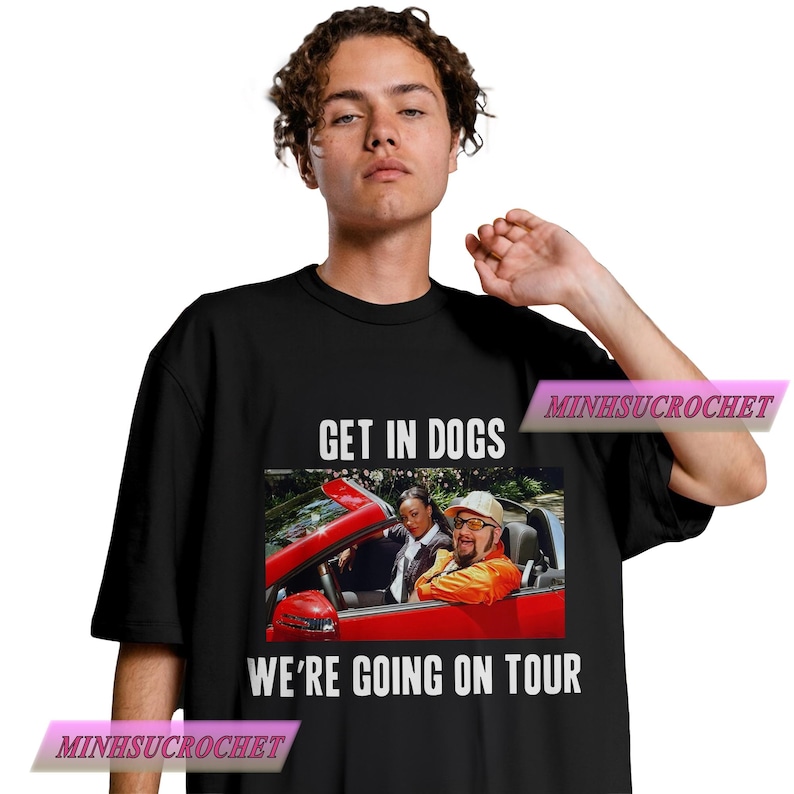 Może przedstawiać: Czarna koszulka z białym napisem "GET IN DOGS WE'RE GOING ON TOUR". Koszulka przedstawia grafikę trzech os&oacute;b w czerwonym kabriolecie. Koszulka ma okrągły dekolt.