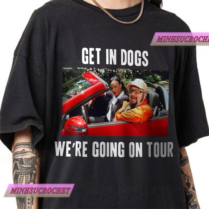 Może przedstawiać: Czarna koszulka z białym napisem "GET IN DOGS WE'RE GOING ON TOUR". Grafika przedstawia dwie osoby w czerwonym kabriolecie. Koszulka ma okrągły dekolt i kr&oacute;tkie rękawy.