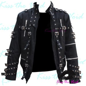 May include: Black cotton jacket with multiple silver buckles and straps. The jacket has a zip closure and a stand-up collar.