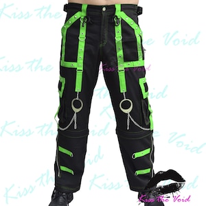 May include: Black cargo pants with neon green straps and silver rings. The pants have multiple pockets and zippers.