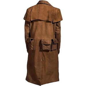 May include: A long, brown suede duster coat featuring a wide shoulder cape, long sleeves, and three large patch pockets on the lower back section. Each pocket is secured with a flap and a single metallic button, providing a structured appearance.