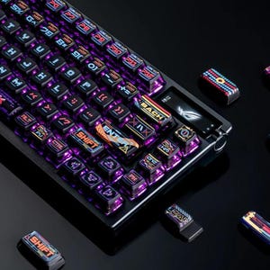 Puede incluir: Un teclado mecánico negro y plateado con teclas iluminadas en púrpura, azul y amarillo. El teclado tiene una variedad de teclas con diseños y texto únicos. Varias teclas sueltas están esparcidas alrededor del teclado.