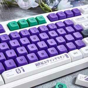 May include: A white mechanical keyboard with purple and green keycaps. The keyboard has a custom keycap set with the text "新世紀エヴァンゲリオン EVANGELION 01 NERV" and a graphic of the Evangelion Unit 01. The keyboard is surrounded by white flowers.